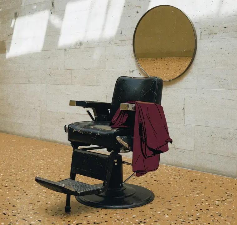 Illustrasjon av en barberstol mot terrazzo og et rundt speil.
